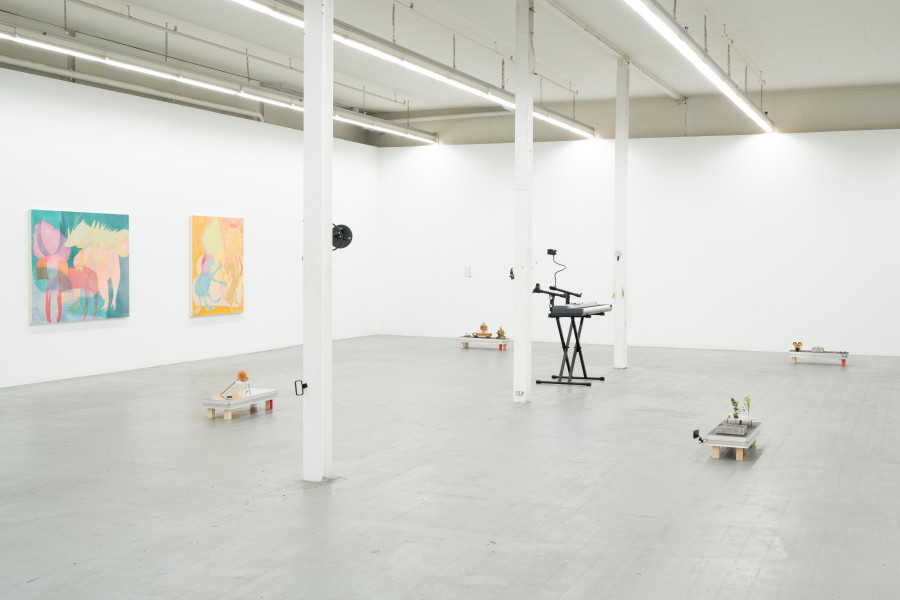 Sara Gassmann, Hevea, 2021, Acryl, Tusche auf Baumwolle, 140 x 120 cm. Yanik Soland & Marianna Angel SOLAND ANGEL, Rotten Flowers, shiny shoes, 2023, Performance + Installation, Bühnenelemente (je ca. 15 × 100 × 30 cm), Metallplatten und -halterungen, Nägel, Plastikblumen, Blumen, Spiegel, Glocken, selbstgebaute Instrumente, Draht, Kenzans (japanische Werkzeuge für Ikebana), Midi-Keyboard, Keyboardständer, Plastikkegel, Holz, Stimmgabel, Masse variabel. Installation view Kunsthaus Baselland. Photo: Finn Curry