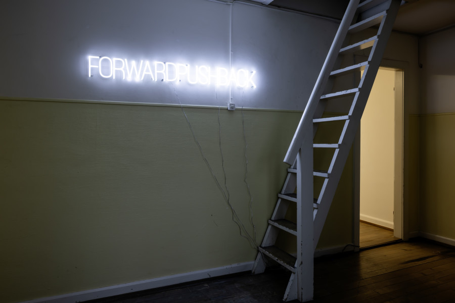 Exhibition View Solo Show Yota Tsotra «Wor(l)ds of borders; view on Yota Tsotra, Pushback/Forward, 2025, programmed light text sign, 140 cm x 15 cm» at Peripherie 8, Basel, 2025 / Photo: Stefan Schmidlin / Courtesy: Peripherie 8