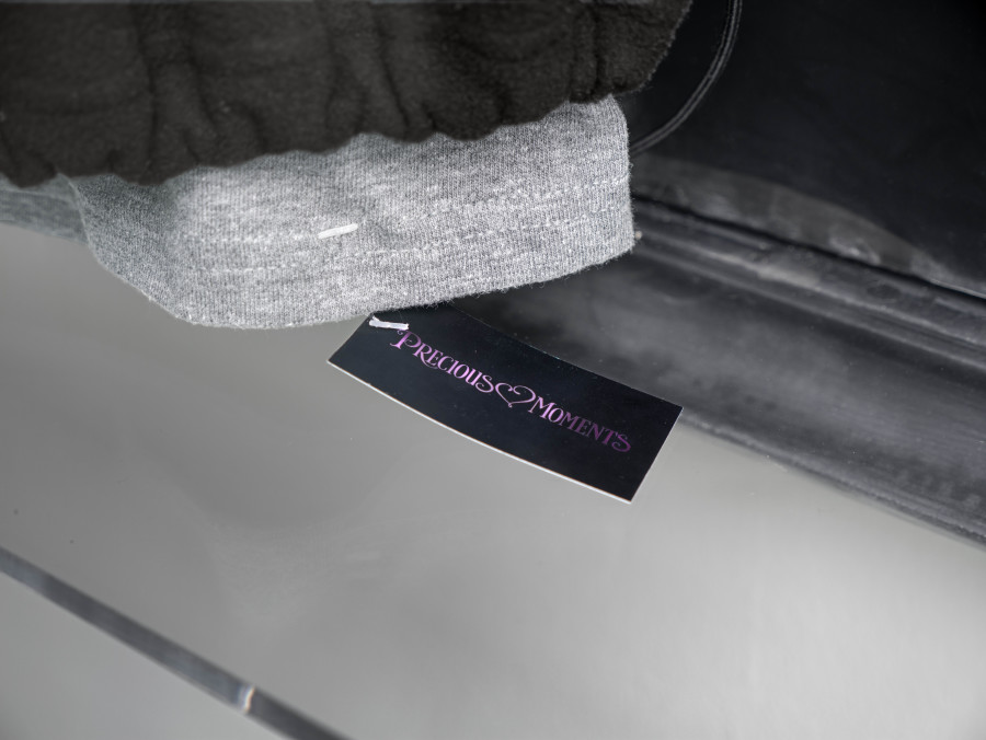 Julian-Jakob Kneer, FANATIC (6) (Detail), 2025, Archival Paysage d'Hiver fleece jacket, Laibach tie pin, Precious Moments t-shirt,
cast rubber and acrilyc glas vitrine, 106 x 76 x 22 cm. Courtesy the artist and Blue Velvet, Zurich. Exhibition views by Andrea Luca Ammann.