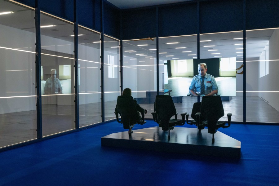 Exhibition view, Pilvi Takala, Close Watch, 2022, Migros Museum für Gegenwartskunst, Multi-channel video installation, spyglass, blue carpet, office chairs. Courtesy Carlos/Ishikawa, Helsinki Contemporary and Stigter van Doesburg. Photo: Flavio Karrer
