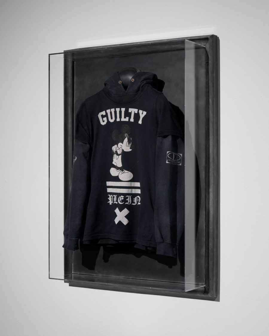 Julian-Jakob Kneer, FANATIC (2), 2025, Archival Misanthropy Records hoodie, Philipp Plein x Disney t-shirt, cast rubber and acrylic glas vitrine, 106 x 76 x 22 cm. Courtesy the artist and Blue Velvet, Zurich. Exhibition views by Andrea Luca Ammann.